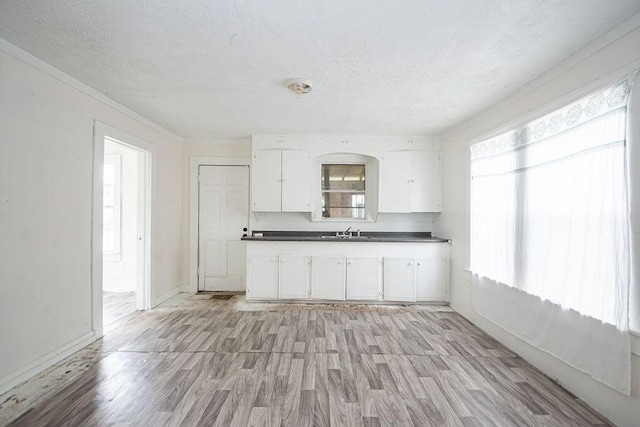 1817 Mcdaniel St, Houston, TX 77093 - kitchen featuring dark countertops, a sink, a textured ceiling, white cabinetry, and light wood-type flooring