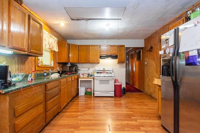 1817 Mcdaniel St, Houston, TX 77093 - kitchen with brown cabinets, a sink, white gas range oven, stainless steel fridge, and under cabinet range hood