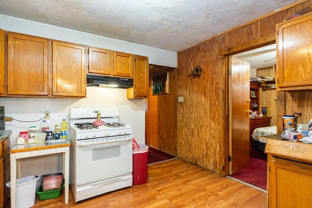 1817 Mcdaniel St, Houston, TX 77093 - kitchen featuring white range with gas stovetop, a textured ceiling, under cabinet range hood, brown cabinets, and light wood finished floors