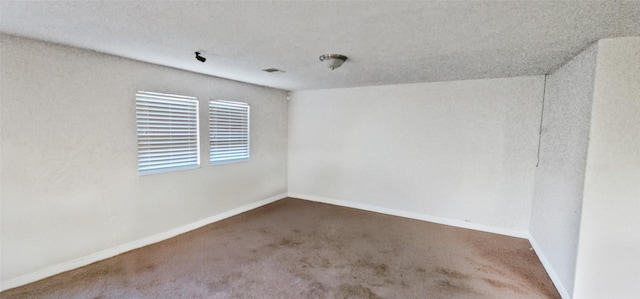carpeted spare room featuring baseboards and a textured ceiling
