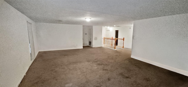 carpeted spare room featuring a textured ceiling, a textured wall, and baseboards