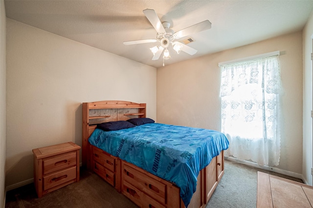 bedroom featuring a ceiling fan, visible vents, and dark colored carpet