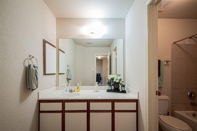 full bath featuring a textured wall, vanity, toilet,  shower combination, and visible vents