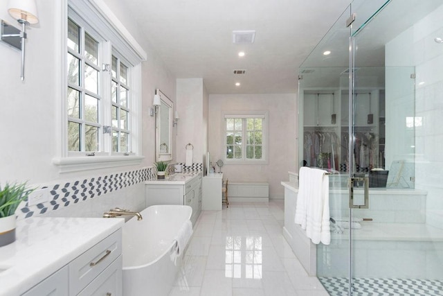 bathroom with a freestanding bath, vanity, recessed lighting, a shower stall, and visible vents