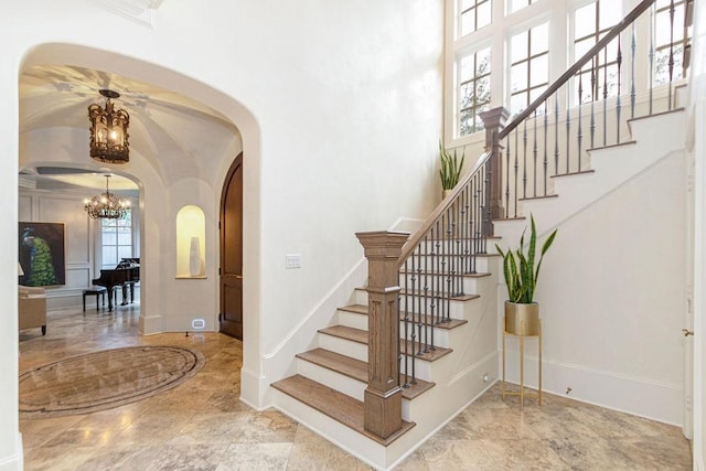 5262 Huckleberry Ln, Houston, TX 77056 - staircase featuring arched walkways, a chandelier, baseboards, a towering ceiling, and marble finish floors