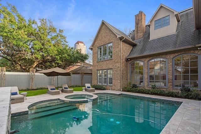 view of swimming pool featuring fence, a patio, and a pool with connected hot tub