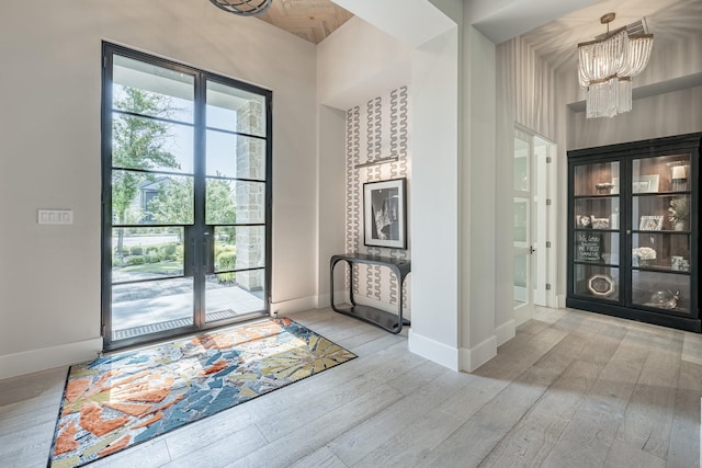 entrance foyer featuring baseboards, french doors, wood finished floors, and a notable chandelier