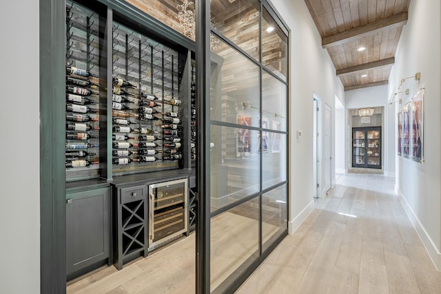 wine cellar with light wood-type flooring, wood ceiling, wine cooler, and beam ceiling