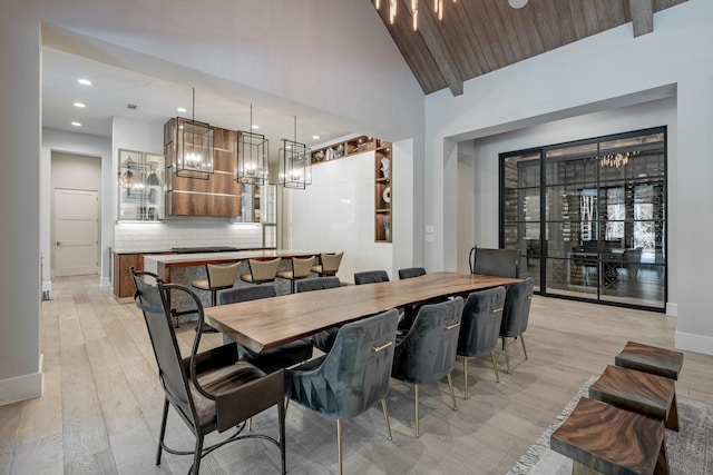 dining area featuring baseboards, a chandelier, lofted ceiling, and light wood finished floors