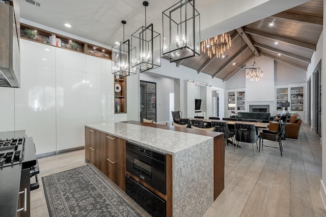kitchen featuring an inviting chandelier, light wood-style flooring, a center island, modern cabinets, and range with gas cooktop