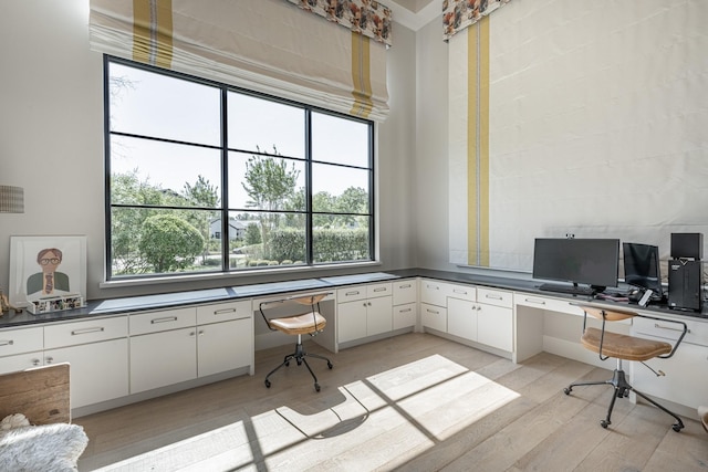 office area with built in study area and light wood-style flooring