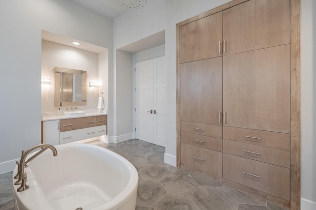 full bathroom with a freestanding tub, baseboards, and vanity