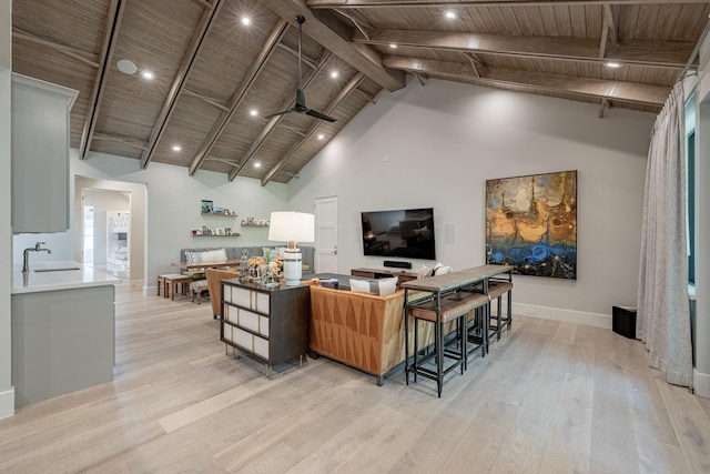 living area with beam ceiling, baseboards, ceiling fan, light wood-type flooring, and wooden ceiling