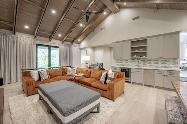 living room with ceiling fan, beverage cooler, high vaulted ceiling, light wood-style flooring, and visible vents