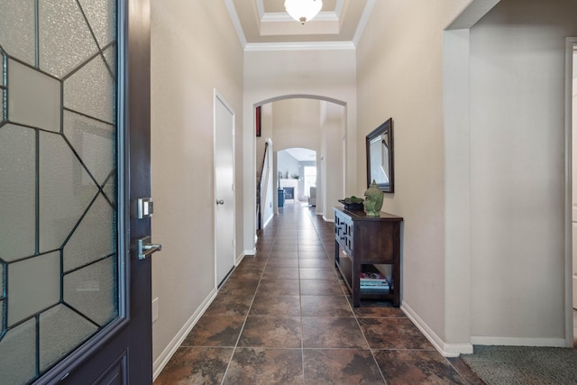 hallway featuring arched walkways, baseboards, and ornamental molding