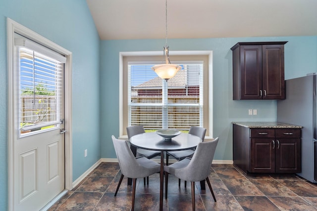 dining area with plenty of natural light, baseboards, lofted ceiling, and stone finish floor