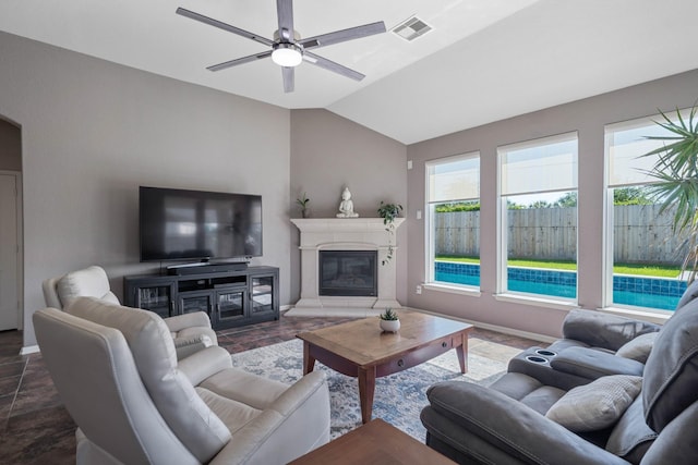 living room featuring visible vents, a glass covered fireplace, lofted ceiling, baseboards, and ceiling fan