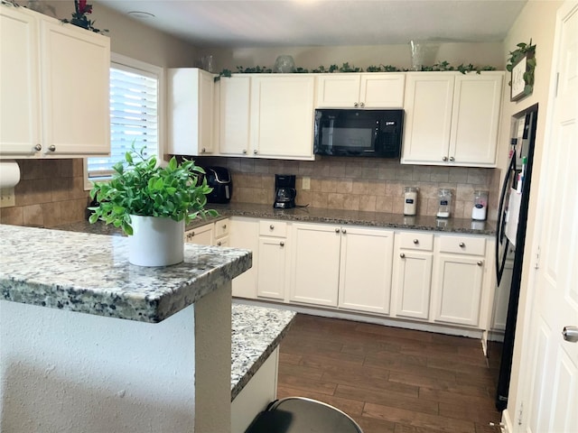 kitchen with white cabinets, dark wood finished floors, black appliances, and tasteful backsplash