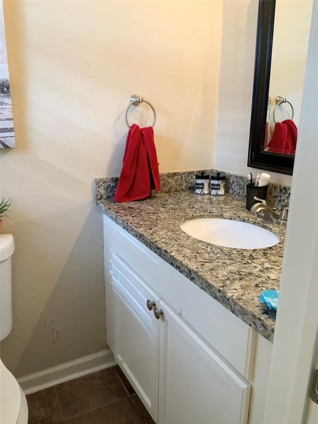 half bathroom featuring vanity, tile patterned flooring, baseboards, and toilet