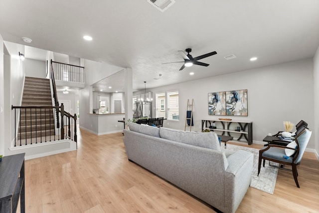 living area with visible vents, stairs, ceiling fan with notable chandelier, light wood finished floors, and recessed lighting