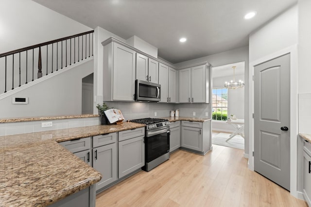 kitchen with backsplash, appliances with stainless steel finishes, light wood-type flooring, gray cabinetry, and recessed lighting