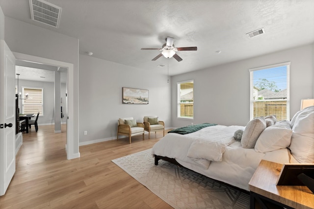 bedroom with baseboards, a ceiling fan, light wood-style flooring, and visible vents