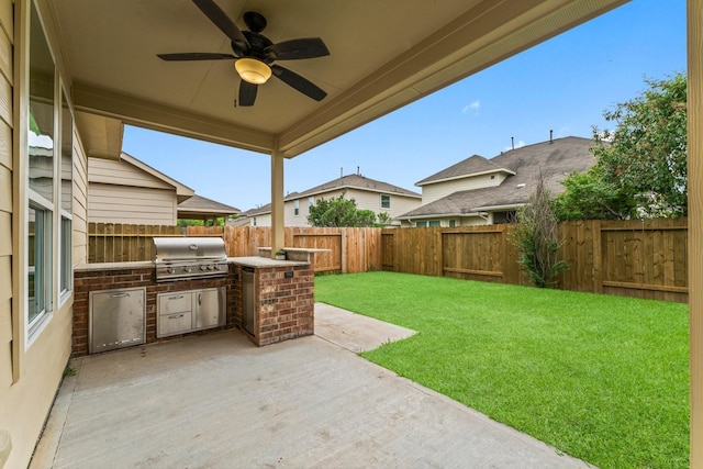 view of patio featuring a fenced backyard, exterior kitchen, ceiling fan, and a grill