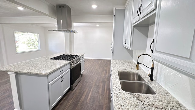 kitchen with island exhaust hood, a center island, stainless steel gas range oven, dark wood finished floors, and a sink