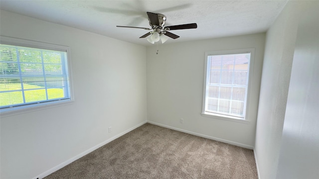 carpeted spare room featuring baseboards and ceiling fan