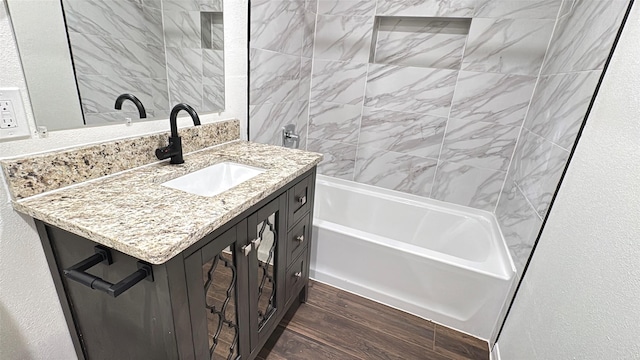 bathroom with shower / bathtub combination, a textured wall, vanity, and wood finished floors