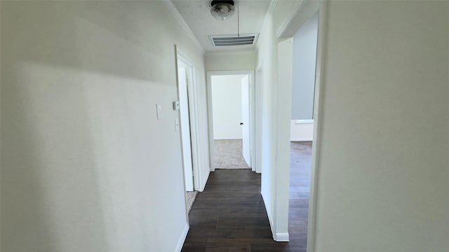 corridor with crown molding, baseboards, visible vents, and dark wood-type flooring