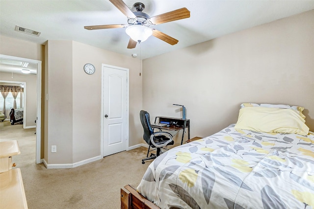 bedroom with visible vents, baseboards, attic access, light colored carpet, and a ceiling fan