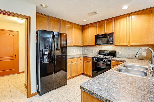 kitchen with decorative backsplash, visible vents, a sink, light tile patterned floors, and black appliances