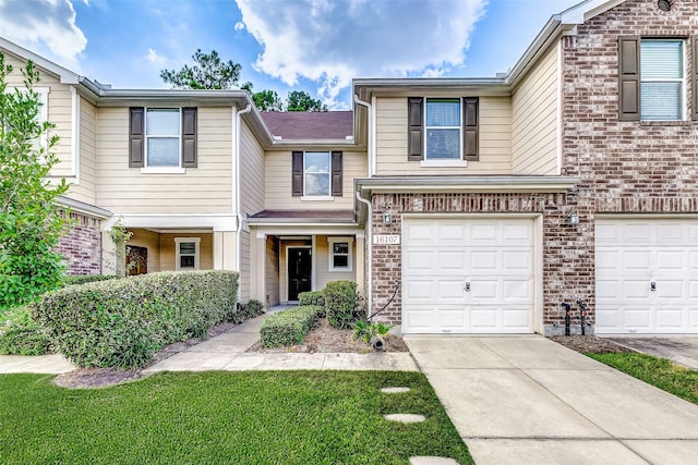 townhome / multi-family property featuring a garage, driveway, and brick siding