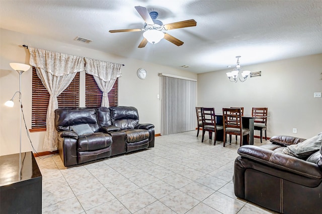 living room featuring light tile patterned flooring, baseboards, visible vents, and ceiling fan with notable chandelier