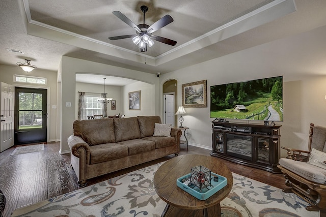 living area with arched walkways, a tray ceiling, baseboards, and hardwood / wood-style flooring