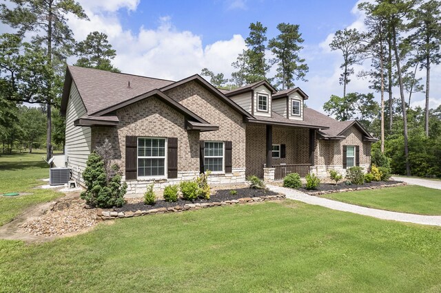 view of front of house featuring a shingled roof, a front lawn, central air condition unit, and covered porch