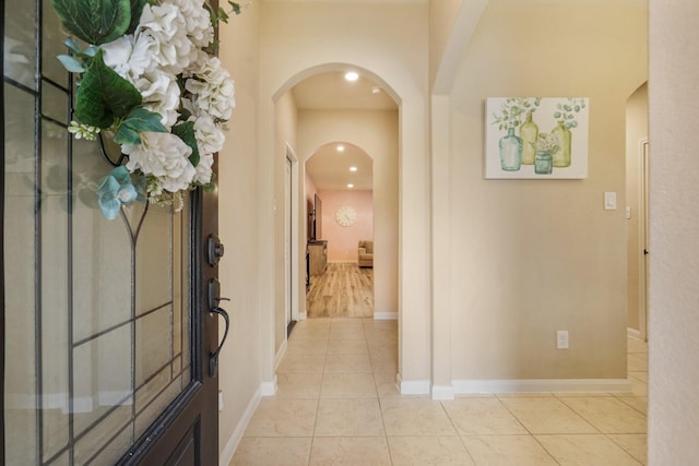 entrance foyer with arched walkways, baseboards, recessed lighting, and light tile patterned flooring