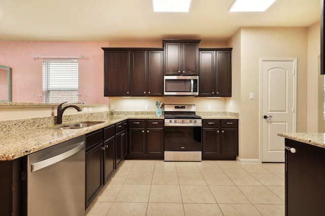 kitchen with light tile patterned flooring, light stone countertops, dark brown cabinets, a sink, and stainless steel appliances