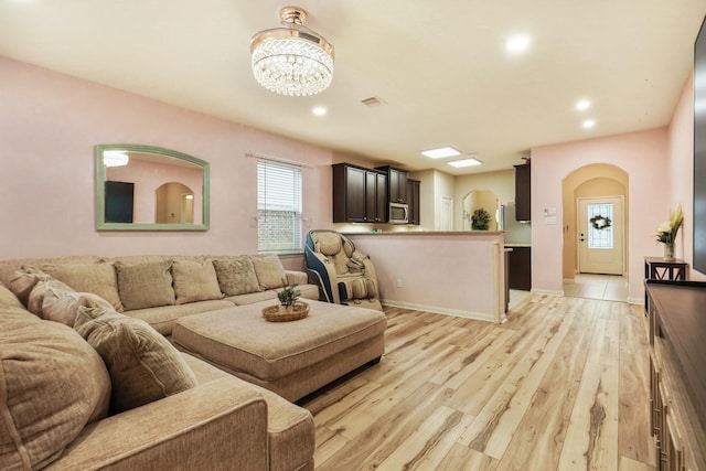 living area featuring arched walkways, a notable chandelier, recessed lighting, and light wood-style floors