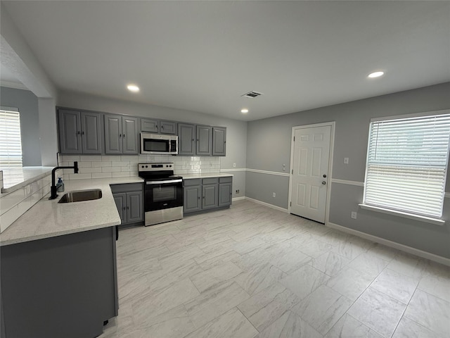 8127 Chancewood Ln, Humble, TX 77338 - kitchen featuring visible vents, marble finish floor, gray cabinets, a sink, and stainless steel appliances