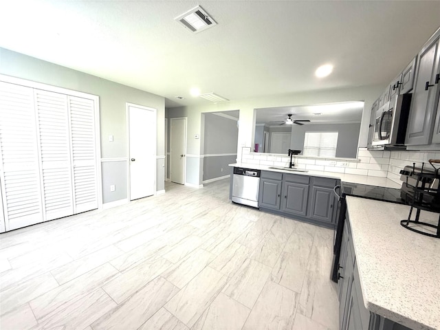 8127 Chancewood Ln, Humble, TX 77338 - kitchen featuring appliances with stainless steel finishes, gray cabinets, a sink, ceiling fan, and decorative backsplash