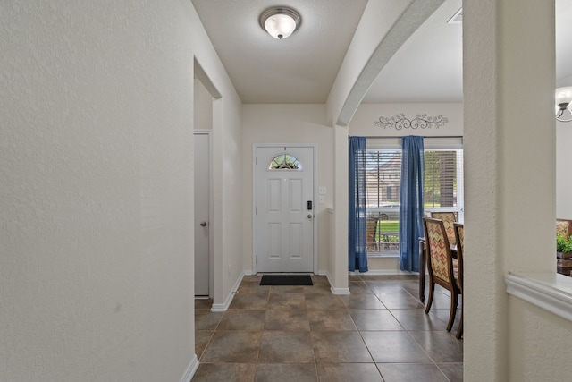 foyer entrance featuring baseboards and arched walkways