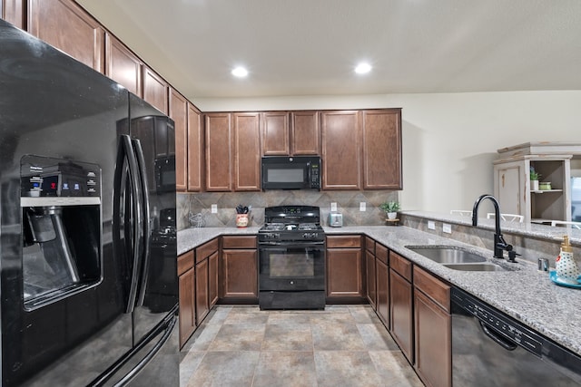 kitchen featuring light stone countertops, a sink, recessed lighting, decorative backsplash, and black appliances