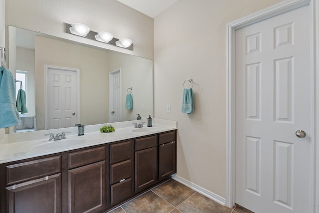 full bath with baseboards, a sink, tile patterned floors, and double vanity