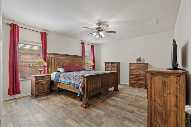 bedroom with visible vents, a ceiling fan, light wood-style flooring, and baseboards