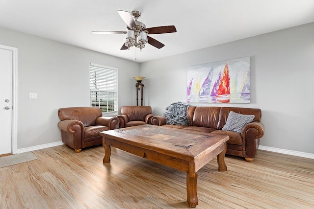 living room featuring a ceiling fan, baseboards, and light wood-style floors
