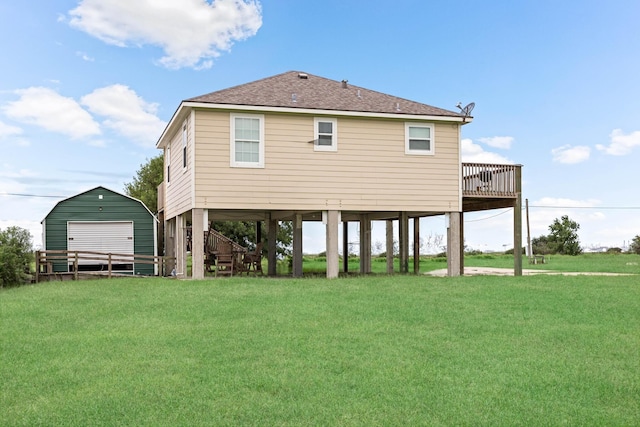 rear view of property with a lawn, an outdoor structure, a shingled roof, and a deck