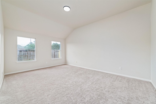 unfurnished room featuring baseboards, carpet flooring, and lofted ceiling