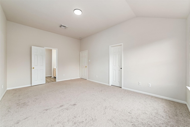 carpeted empty room featuring baseboards, visible vents, and lofted ceiling